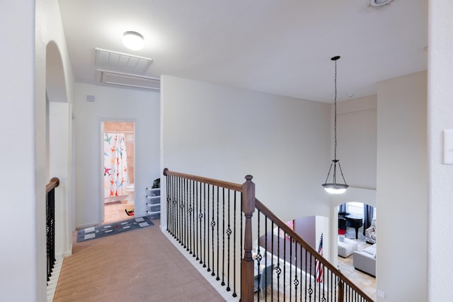 hallway featuring an upstairs landing, carpet, visible vents, and a healthy amount of sunlight