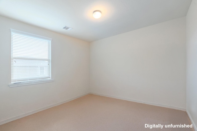 empty room with baseboards, visible vents, and light carpet