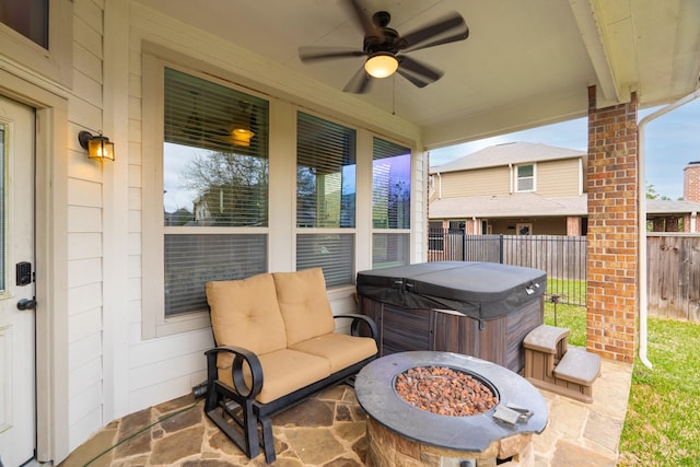 view of patio featuring fence, an outdoor fire pit, ceiling fan, and a hot tub