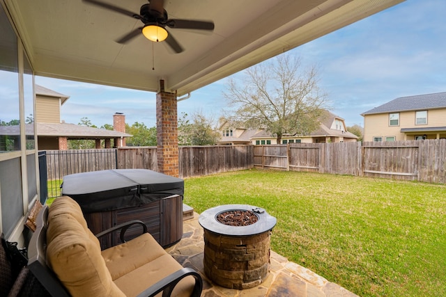 view of patio with a fenced backyard, an outdoor fire pit, ceiling fan, and a hot tub