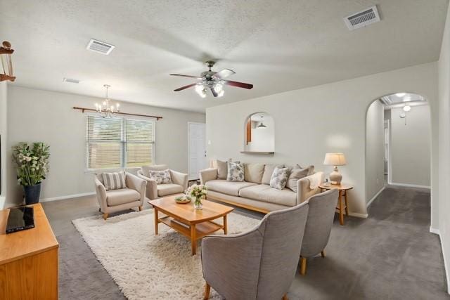 living room with arched walkways, visible vents, ceiling fan with notable chandelier, and baseboards