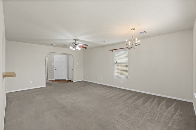 empty room featuring visible vents, baseboards, ceiling fan with notable chandelier, arched walkways, and dark colored carpet