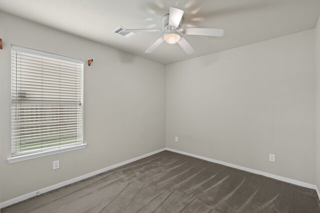 empty room featuring a ceiling fan, baseboards, and dark colored carpet