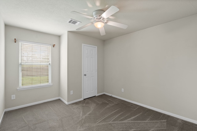 unfurnished bedroom with visible vents, baseboards, ceiling fan, dark carpet, and a textured ceiling