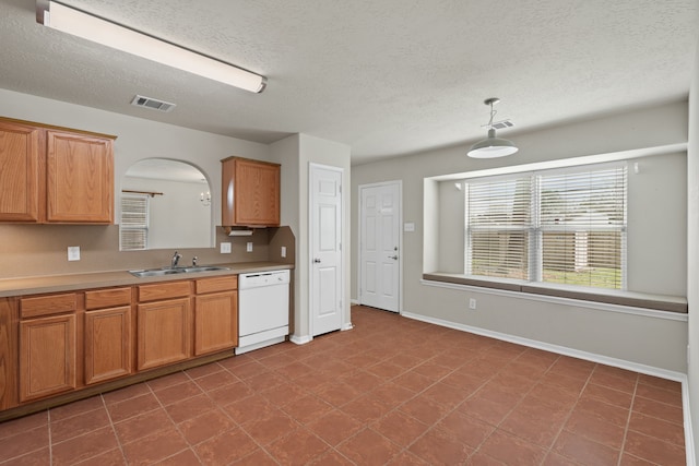 kitchen with visible vents, arched walkways, a sink, light countertops, and dishwasher