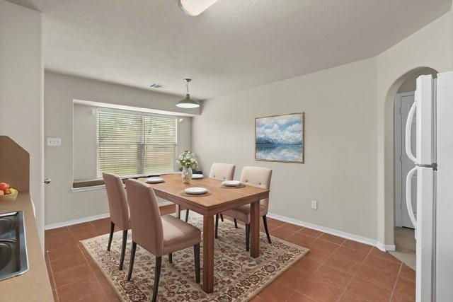 tiled dining room with a sink, baseboards, arched walkways, and visible vents