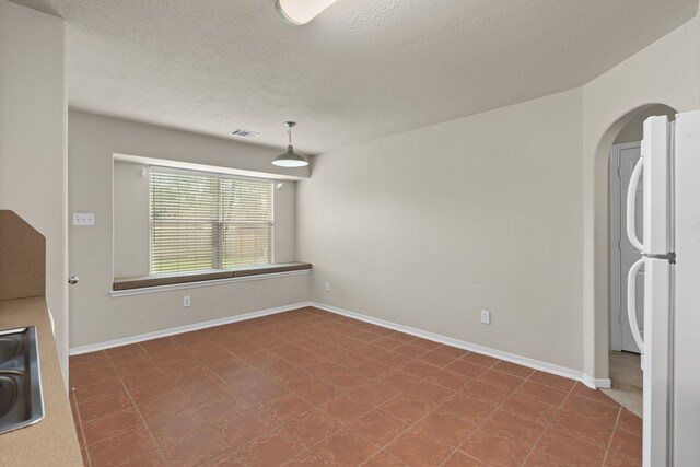 unfurnished dining area featuring baseboards, visible vents, arched walkways, a sink, and a textured ceiling