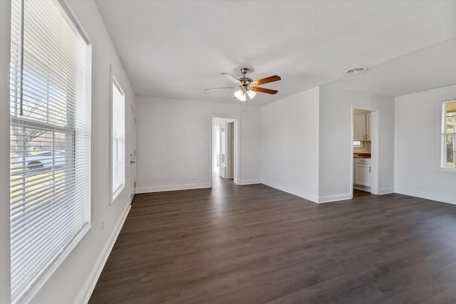 unfurnished room featuring plenty of natural light, baseboards, and dark wood-style flooring