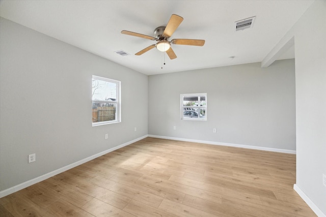 spare room featuring light wood-style flooring, visible vents, and a wealth of natural light