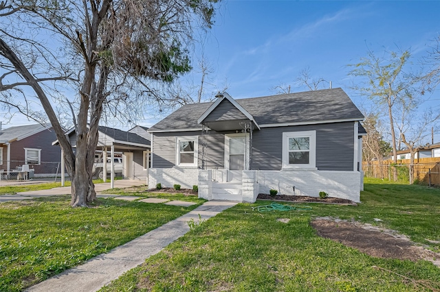 bungalow featuring brick siding, a shingled roof, a front yard, and fence