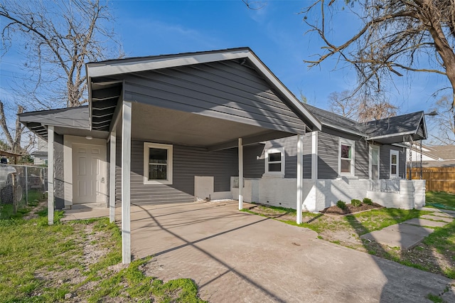 rear view of property featuring an attached carport and fence