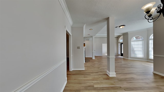 foyer with baseboards, decorative columns, light wood-style floors, a textured ceiling, and crown molding