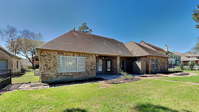 view of front of home with brick siding, roof with shingles, a front lawn, and fence