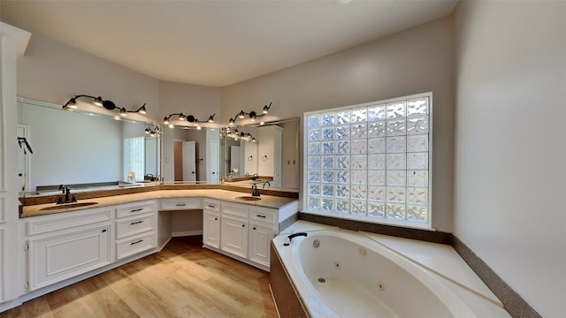 bathroom with a sink, a tub with jets, wood finished floors, and double vanity