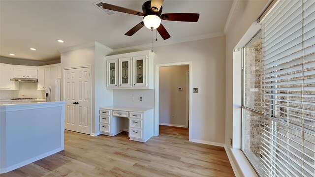 kitchen featuring light countertops, crown molding, fridge with ice dispenser, light wood-type flooring, and backsplash