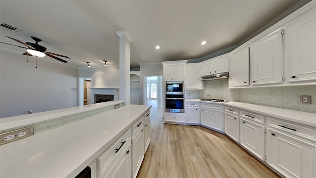 kitchen with visible vents, appliances with stainless steel finishes, under cabinet range hood, crown molding, and tasteful backsplash