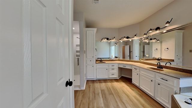 bathroom with a sink, visible vents, wood finished floors, and double vanity