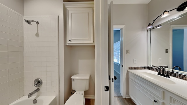 bathroom featuring wood finished floors, toilet, vanity, and washtub / shower combination