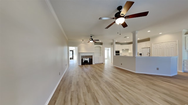 unfurnished living room featuring light wood finished floors, baseboards, ornamental molding, recessed lighting, and a fireplace