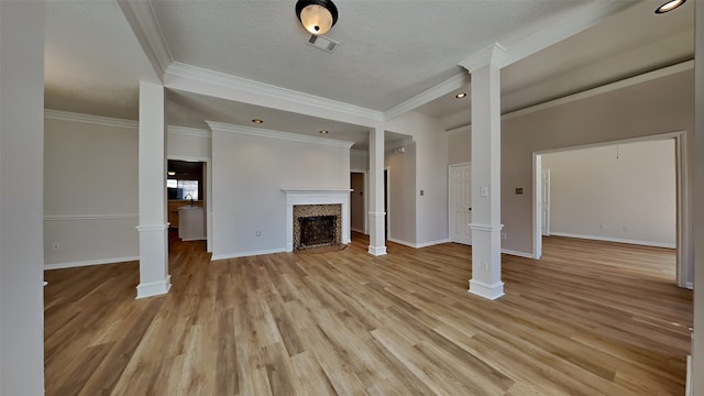 unfurnished living room with baseboards, a tile fireplace, light wood-style floors, a textured ceiling, and ornate columns