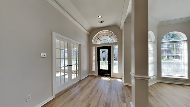 foyer with visible vents, lofted ceiling, ornamental molding, light wood finished floors, and baseboards