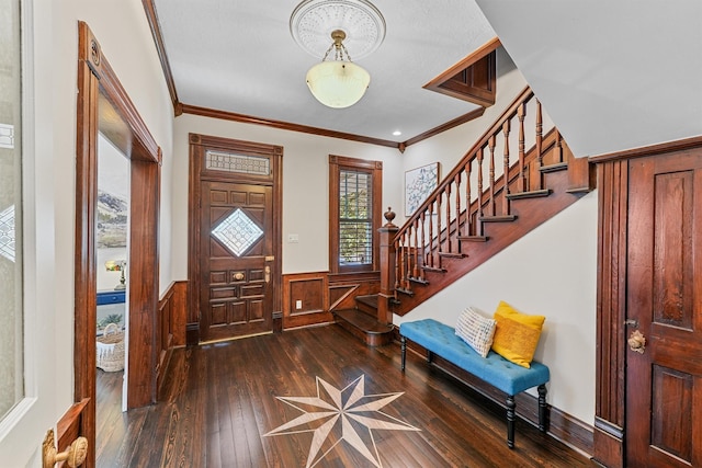 entryway featuring stairs, dark wood-type flooring, ornamental molding, and wainscoting