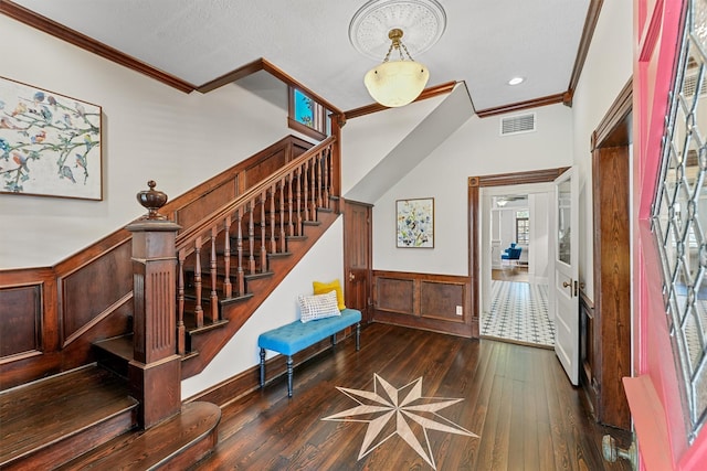 foyer entrance featuring visible vents, wainscoting, crown molding, and hardwood / wood-style floors