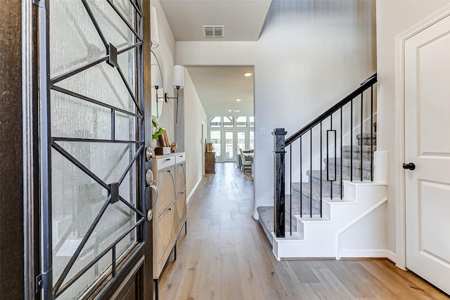 entrance foyer with stairs, visible vents, light wood-type flooring, and baseboards