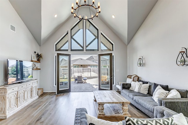 living area with visible vents, high vaulted ceiling, a chandelier, and light wood finished floors