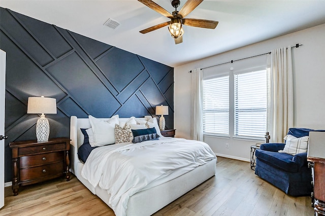 bedroom with light wood finished floors, visible vents, a ceiling fan, and baseboards