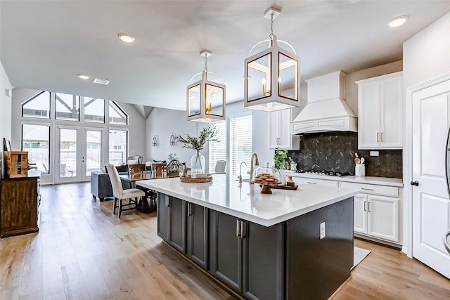 kitchen featuring custom exhaust hood, white cabinets, visible vents, and white gas stovetop