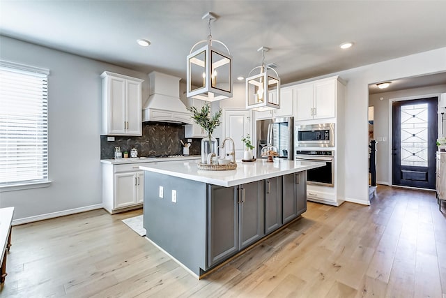 kitchen with tasteful backsplash, white cabinetry, appliances with stainless steel finishes, light countertops, and custom exhaust hood