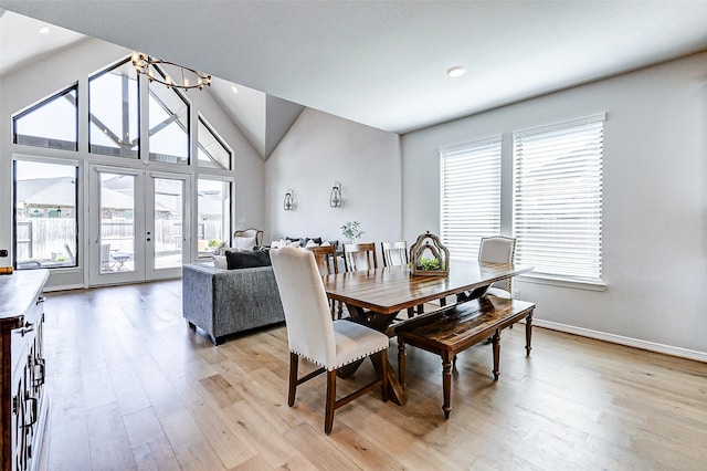 dining room featuring light wood finished floors, a chandelier, french doors, and baseboards