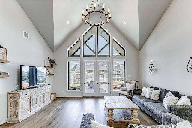 living area with visible vents, french doors, an inviting chandelier, wood finished floors, and high vaulted ceiling