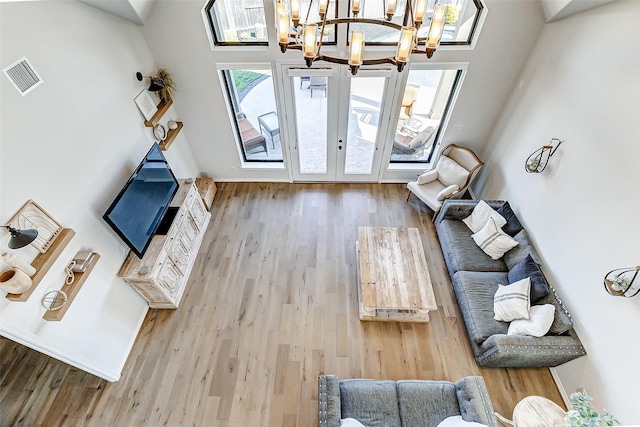 living room with visible vents, a notable chandelier, wood finished floors, and french doors