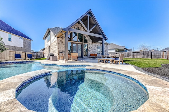 view of swimming pool with a pool with connected hot tub, a patio area, and a fenced backyard