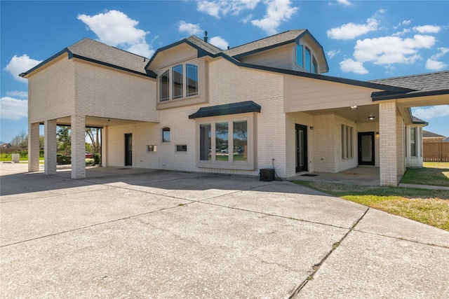 back of property with brick siding, driveway, and a shingled roof