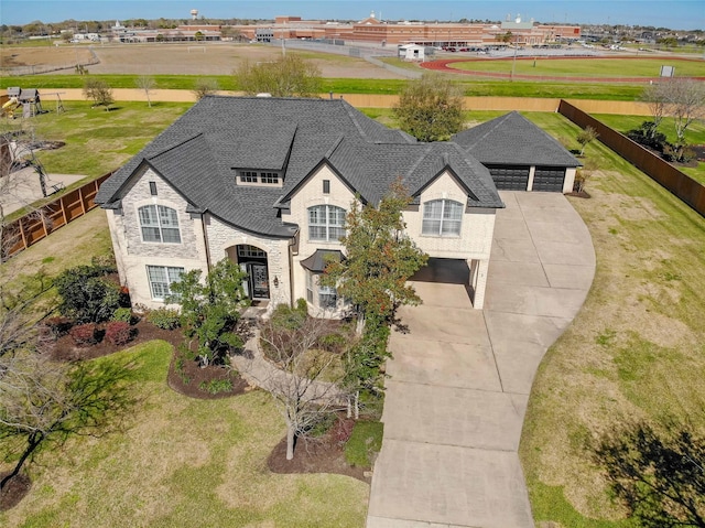 view of front of property featuring fence, roof with shingles, concrete driveway, stone siding, and a garage