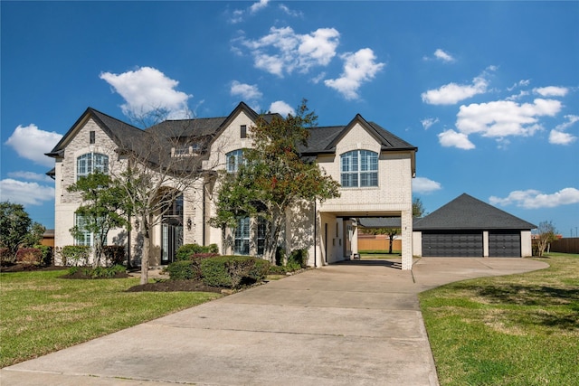 french country style house with a front lawn, a carport, and an outdoor structure