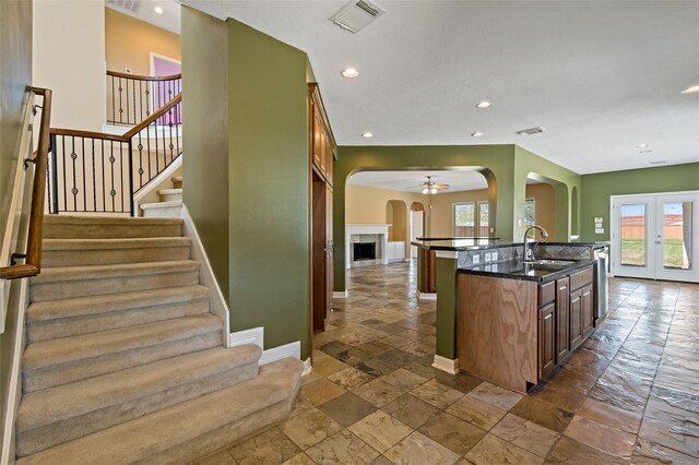 kitchen featuring visible vents, a sink, stone tile floors, open floor plan, and arched walkways