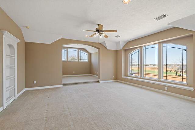 empty room with visible vents, a textured ceiling, carpet, and lofted ceiling