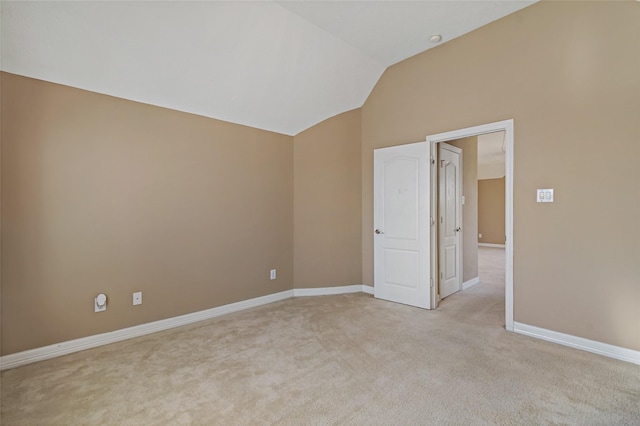 unfurnished room featuring vaulted ceiling, light colored carpet, and baseboards