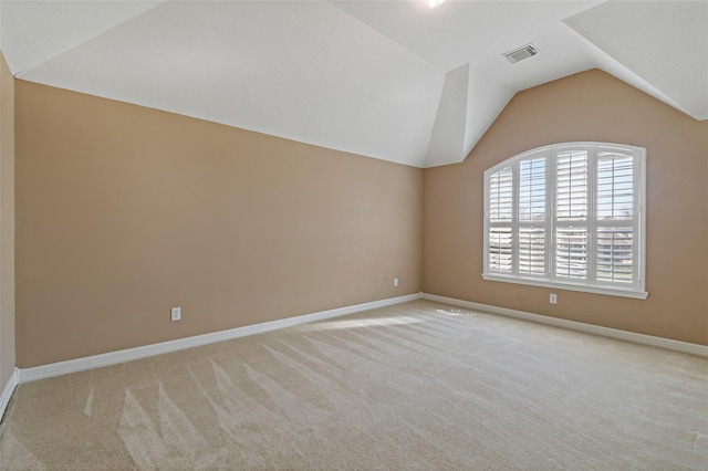 carpeted empty room featuring lofted ceiling, baseboards, and visible vents