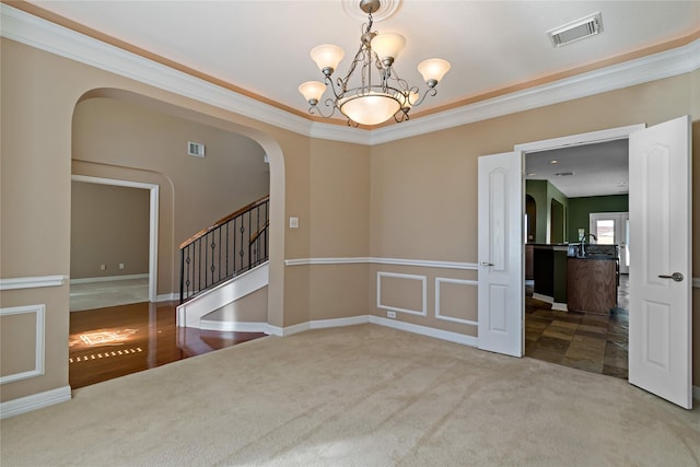 empty room featuring arched walkways, visible vents, crown molding, and carpet