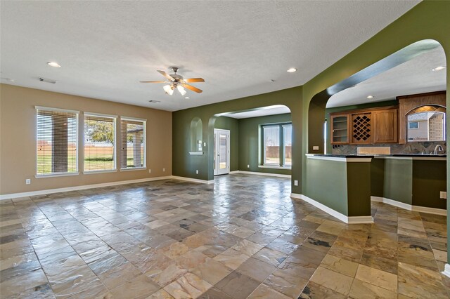 unfurnished living room with stone tile flooring, recessed lighting, and baseboards