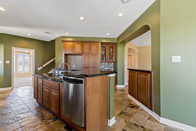 kitchen with tasteful backsplash, visible vents, a center island with sink, dishwasher, and a sink