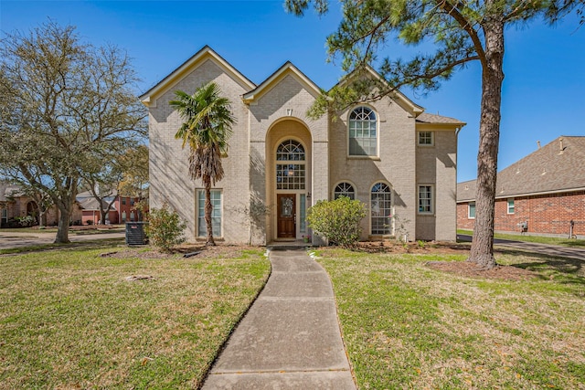 view of front of house with cooling unit, brick siding, and a front yard