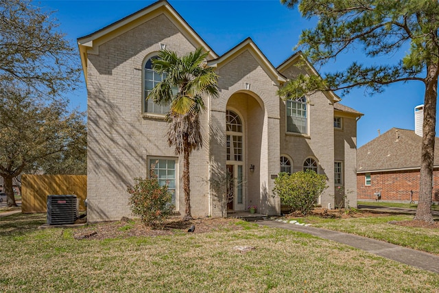 view of front of home with brick siding, cooling unit, a front lawn, and fence