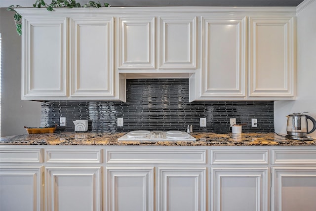 kitchen with white electric cooktop, backsplash, and white cabinetry