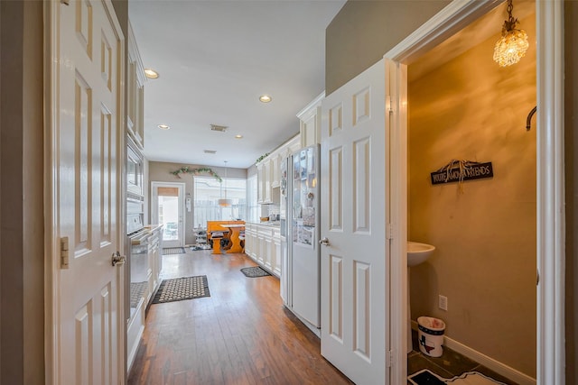 corridor featuring visible vents, recessed lighting, baseboards, and dark wood-style flooring